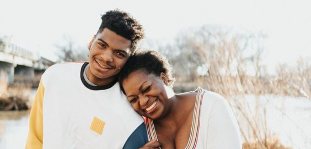 black son with mother standing outside happily